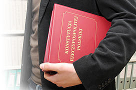 Mężczyzna trzyma okładkę z napisem Konstytucja Rzeczypospolitej Polskiej
